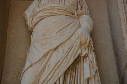 Close-up of carved drapery on an ancient stone sculpture of a woman