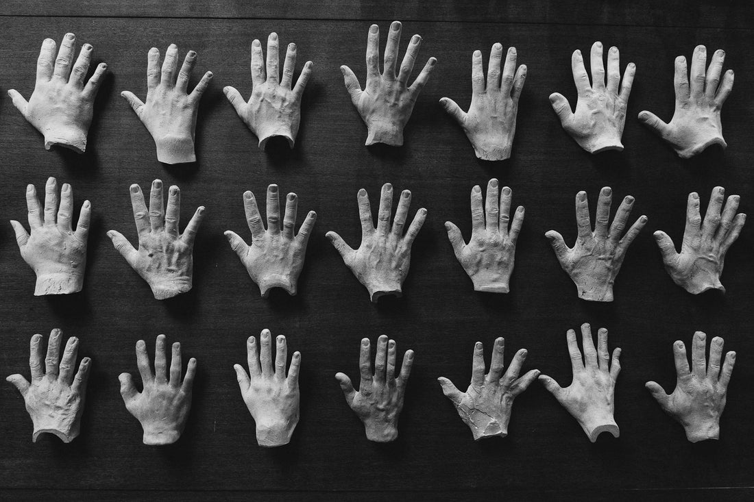 Plaster cast sculptures of hands arranged on a dark background