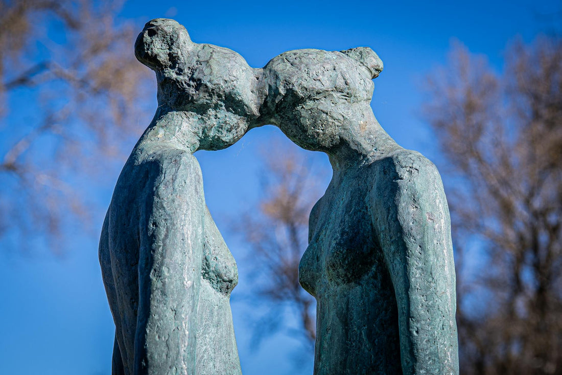 Two abstract figurative sculptures touching heads, the negative space between them framing the form