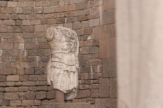Ancient marble torso fragment, headless and armless, against weathered stone