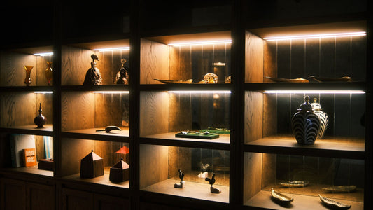 Warmly lit wooden shelves holding ceramic sculptures and vessels in a home interior