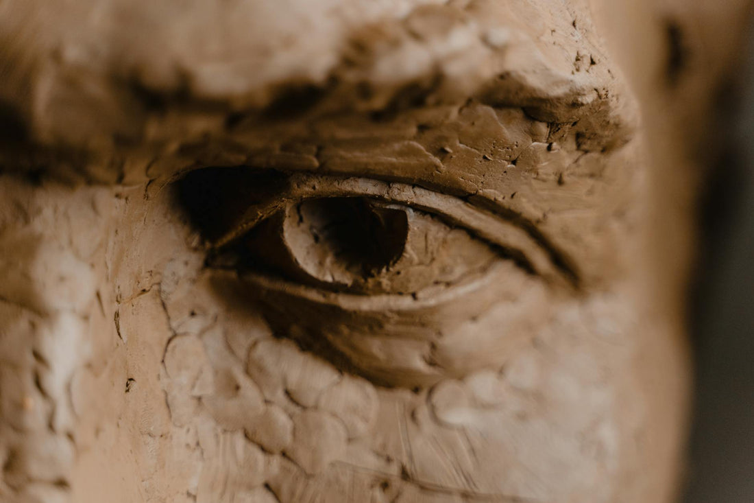 Close-up detail of a clay sculpture's eye showing the form and gaze of a hand-built figurative work