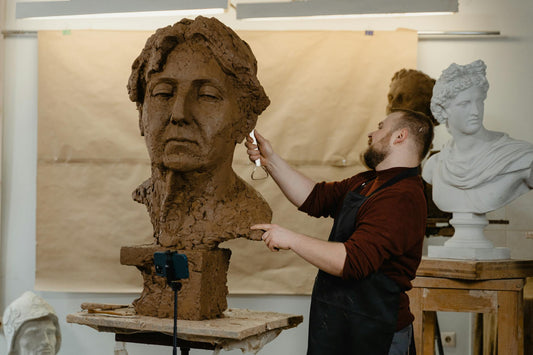 A figurative sculptor at work on a clay bust in a working studio