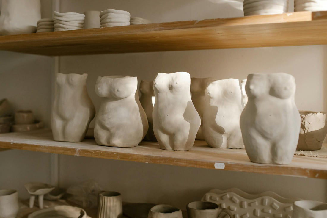 Hand-built ceramic figurative sculptures arranged in a pottery studio