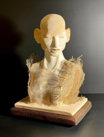 Sculpture of a human bust with textured surface on a dark background