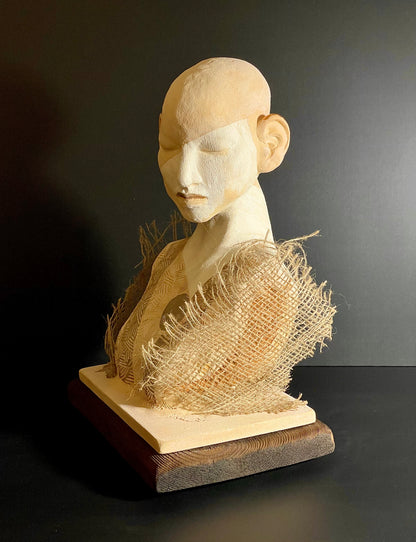 Sculpture of a head with textured fabric on a dark background