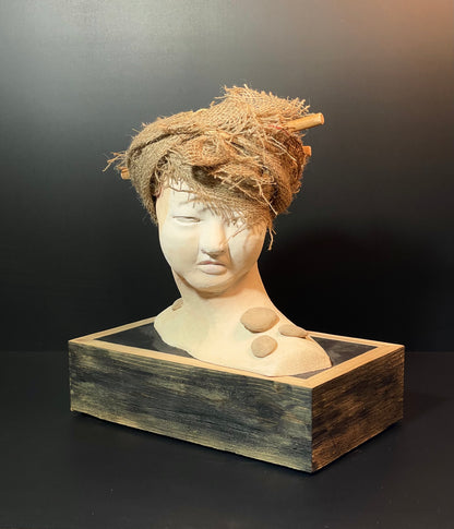 Bust of a woman wearing a woven headpiece on a dark background