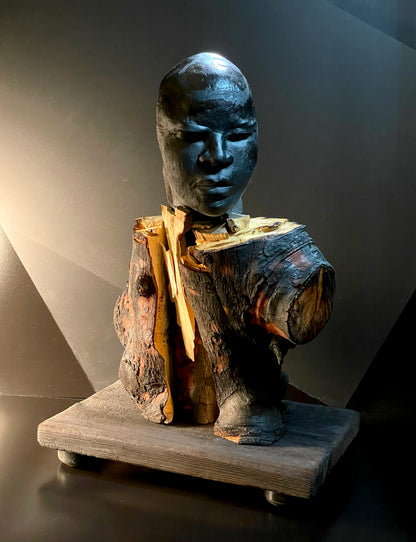 Sculpture of a figure's face on top of a wooden base front