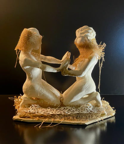 Decorative sculpture of two figures with interacting on a dark background