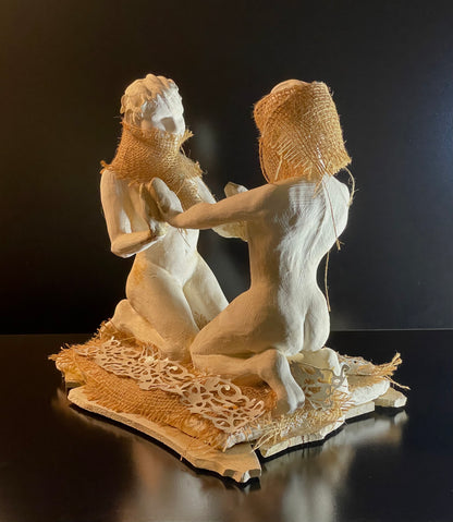 Decorative sculpture of two figures with interacting on a dark background
