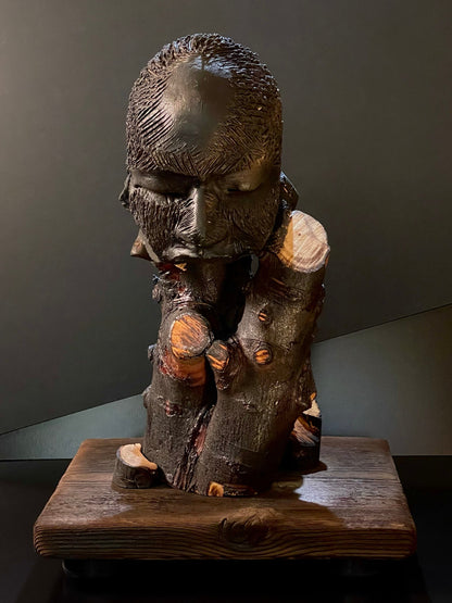 Sculpture of a figure's face on top of a wooden base front view