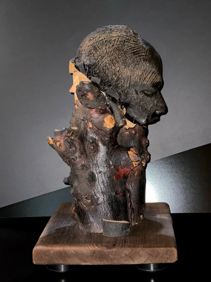 Sculpture of a figure's face on top of a wooden base right side
