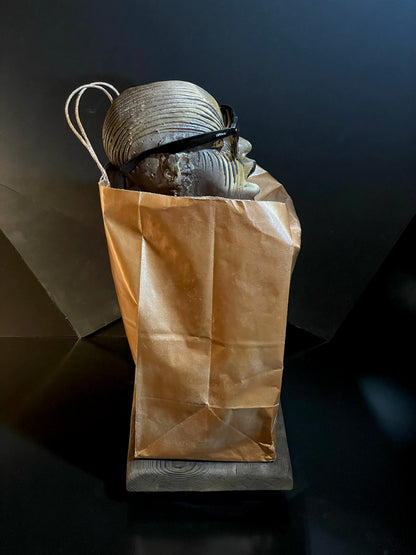 Brown paper bag with sculpture of a face with sunglassess on it