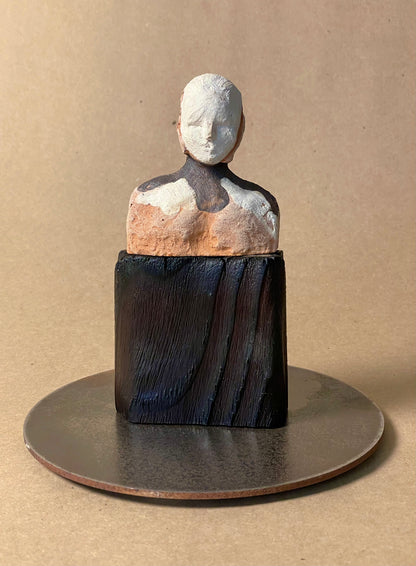 A sculpture titled 'Endless Ride' featuring a stylized, abstract depiction of a seated figure with a round, solid-colored body and a flat, disc-like base.