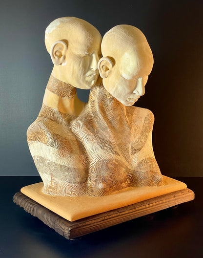 Abstract sculpture of two faces on a dark background