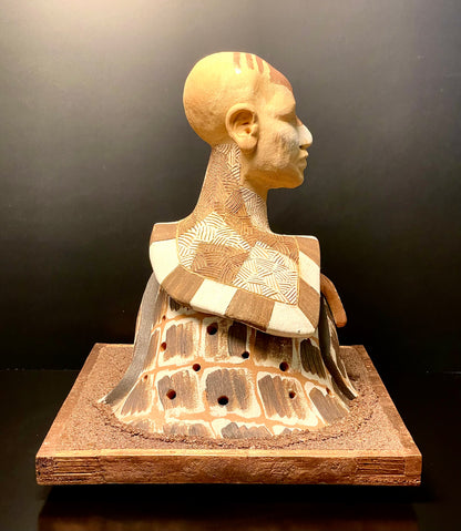 Ceramic sculpture of a human head and shoulders on a dark background