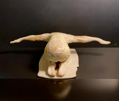  sculpture of a nude figure praying on a dark background