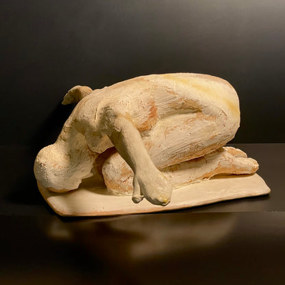 Clay sculpture of a man praying on a dark background