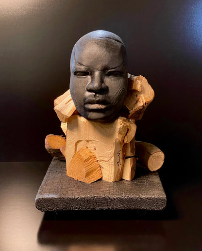 Sculpture of a figure's face on top of a wooden base front angle view