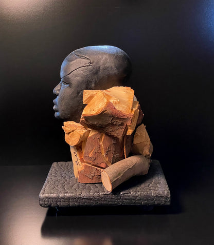 Sculpture of a figure's face on top of a wooden base left side angle