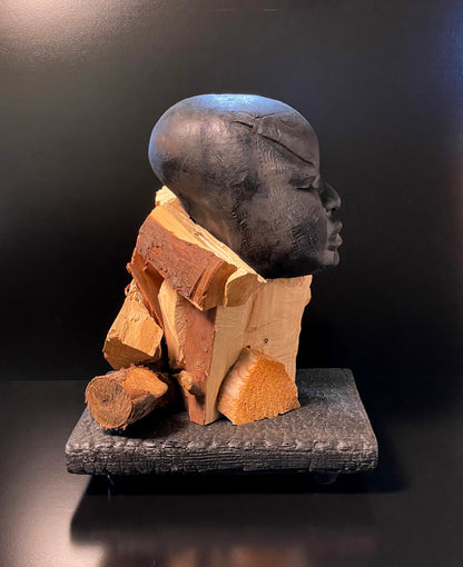 Sculpture of a figure's face on top of a wooden base right side angle