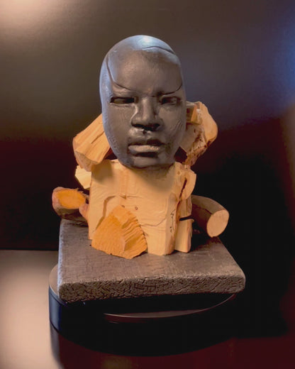 Video of Sculpture of a figure's face on top of a wooden base