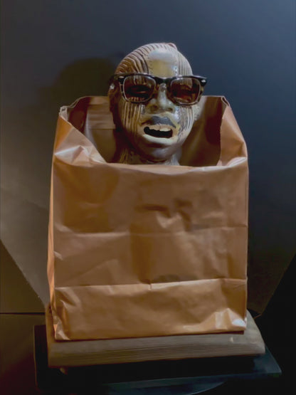 video of the sculpture of a mans face with sunglasses in a brown paper bag